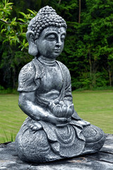 Eine Buddhastatue vor grünem Hintergrund in Nahaufnahme