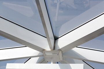 Architectural structure, glass roof. Thick beams painted white converge at a central point. The...