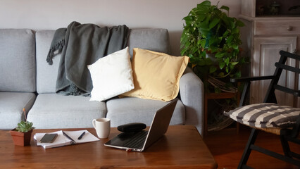 Notebook, pen ,a cup of tea and electronic devices at home living room.Work al home concept