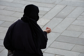 A woman dressed in black robe and headscarf ask for charity donations in Tbilisi, Georgia.