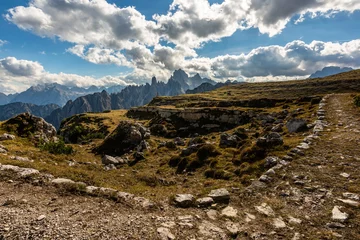 Fotobehang Rocky footpaths below the monumental peak of Tre Cime with the cloudy blue sky © Simona_Mach