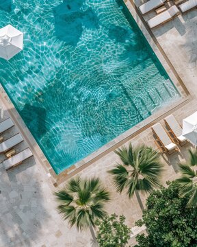 Aerial view of a swimming pool with white sun loungers and umbrellas