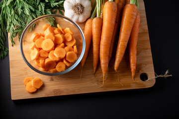 sliced carrots in a round glass bowl and whole carrots on the table