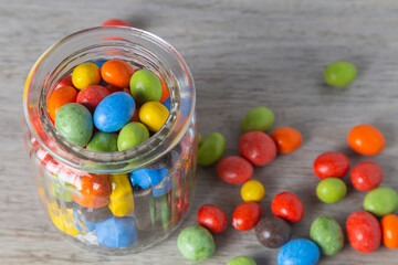 Peanuts in chocolate multi-colored glaze in a glass jar. Close up