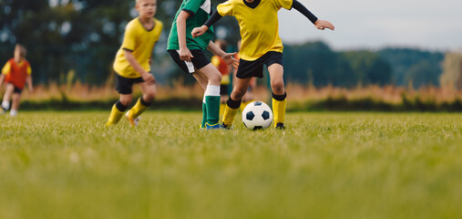Boys in Football Teams Kicking Ball on Grass Field. Children Playing Soccer Match. Junior-level Soccer Player Dribbling Ball And Compete With Defender