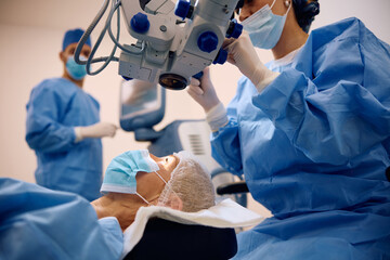 Mature female patient undergoing eye surgery at ophthalmology clinic.