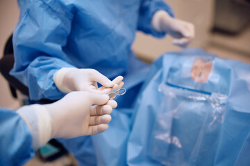 Close up of nurse assisting eye surgeon in operating room at  clinic.