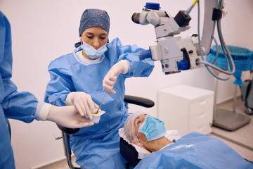 Female doctor during eye surgery at ophthalmology clinic.