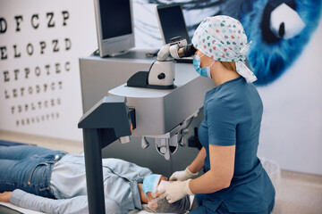 Medical eye expert and her patient during laser surgery at clinic.