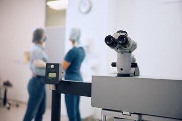 Close up of ophthalmic microscope with doctor and patient in background.