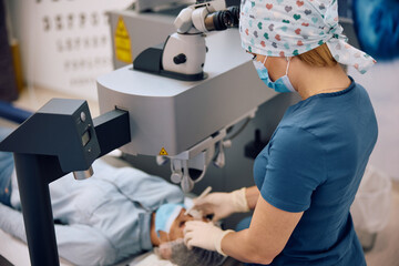 Female ophthalmologist performing laser eye surgery at  clinic.