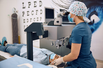 Medical eye expert performing laser surgery at ophthalmology clinic.