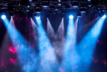 Bright stage spotlights shining through the smoke on a dark background