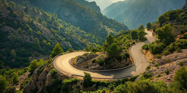 A road with curves meanders through a mountain range, showcasing the rugged terrain and vast landscape