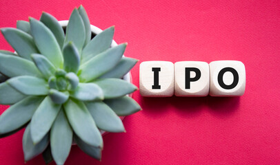 IPO- Initial Public Offering symbol. Concept word IPO on wooden cubes. Beautiful red background...