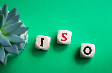 ISO standards quality control symbol. Concept word ISO on wooden cubes. Beautiful green background...