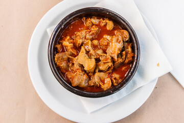 Stewed chicken gizzards in a sauce in a bowl on the table. Top view. Typical Spanish appetizer