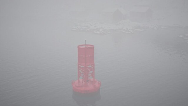 A red metal buoy effortlessly floats on the cold waters of the Norwegian sea.