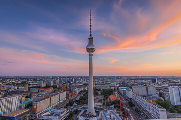 Obraz premium Sunset over the roofs of Berlin. Skyline with television tower in the evening in the center of the capital of Germany. Tallest building on Alexanderplatz with the Red Town Hall under a cloudy sky