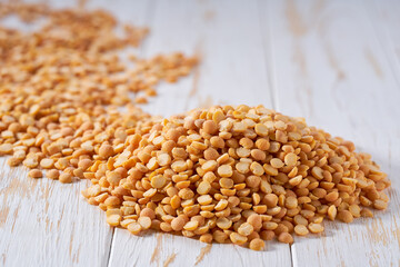 Pile of raw dried peas on a white wooden table. Heap of yellow peas on a white wooden table.