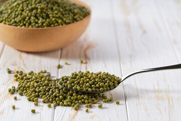 metal spoon with mung beans on a light table, selective focus.