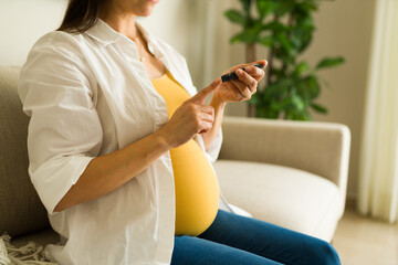 Pregnant woman using a diabetes monitor at home
