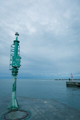 Port and pier equipment, little beacon on the pier in a Riviera Romagnola beach location. dramatic sky in a winter afternoon. Winter sea. Moody and gloomy day.