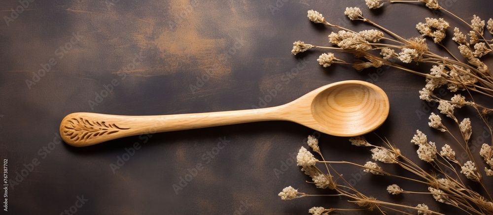 Poster A kitchen utensil, wooden spoon, is placed on tableware next to dried flowers. It is essential for cooking staple foods and preparing dishes in various cuisines