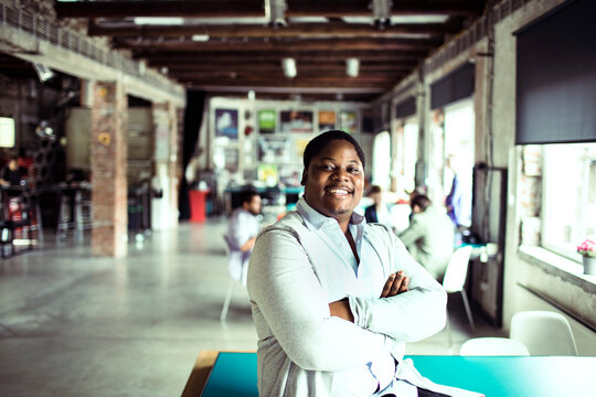 Young man of african ethnicity looking at the camera with crossed arms while working in a startup company office