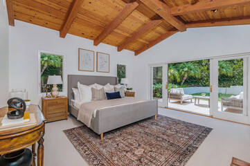 a bedroom has an elegant wooden ceiling, carpet and large sliding glass doors