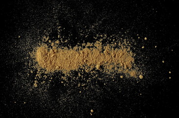 Ginger root powder scatter isolated on black, top view	