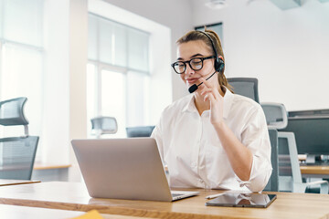 An attentive customer service professional operator is a woman with a headset conducts a call, her...