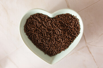 Chocolate Flakes inside a clean green heart shaped bowl in aerial view