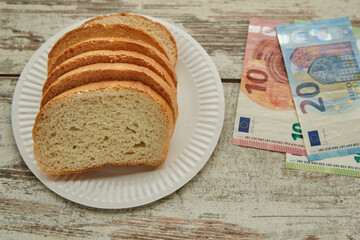  Bread on a plate on the table next to euro bills, sale of bread in Europe, rising food prices in Europe