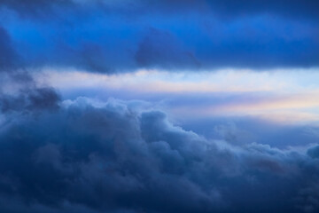 Blue clouds in the sky and a strip of light on the horizon, sky with blue clouds and sunlight in...