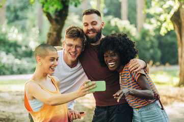 Portrait of interracial friends taking selfies in a park for social media.