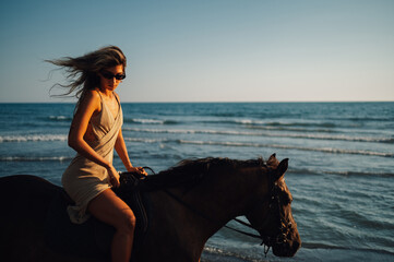 A young lady is riding a horse near the ocean.