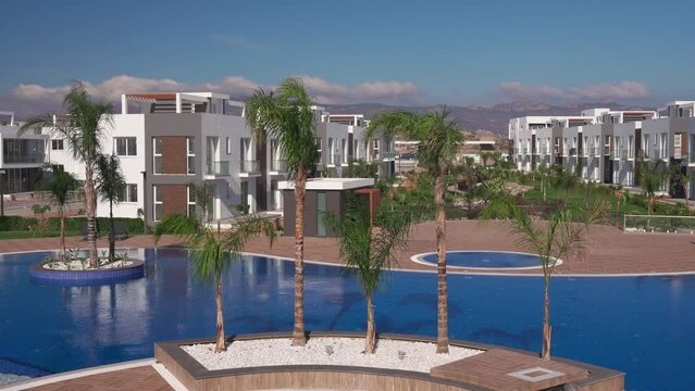 Luxury residential playground with pool, palm trees, modern villas, mountain backdrop, sunny upscale estate for affluent lifestyle promo real estate showcase.