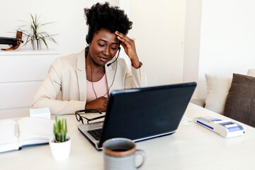 Stressed business woman working from home on laptop looking worried, tired and overwhelmed.