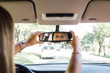 Driver woman adjusting the rear view mirror of her car.