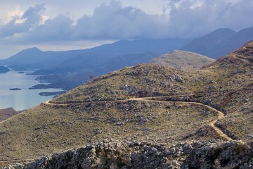The gravel road on the side of a mountain slope above Lake Skadar, Montenegro. Panoramic road no. 3 Virpazar - Ulcinj near Donji Murici.