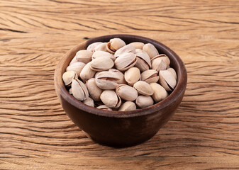 Salted roasted pistachios on a bowl over wooden table