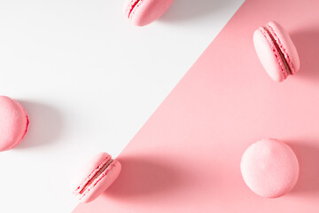 Pink macaroons on pink and white background. Sweet background. Flat lay, top view, copy space