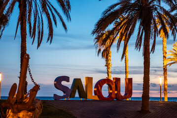 colorful letters of Salou town, palm trees andl beach at sunset, Catalonia, Spain - obrazy, fototapety, plakaty