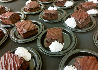 Pieces of chocolate cake with whipped cream on plastic plates