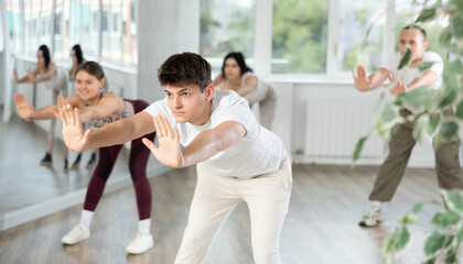 Young guy and international dancers preparing their modern dance performance at light dance studio