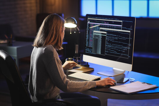 Female programmer working with computer in office at night