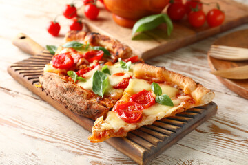 Fototapeta na wymiar Board with slices of tasty pizza Margarita on light wooden background