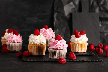 Boards of tasty raspberry cupcakes on black background