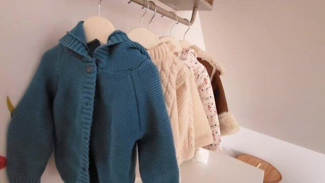 Selection of warm knitted sweaters hanging on a rack signaling seasonal wardrobe